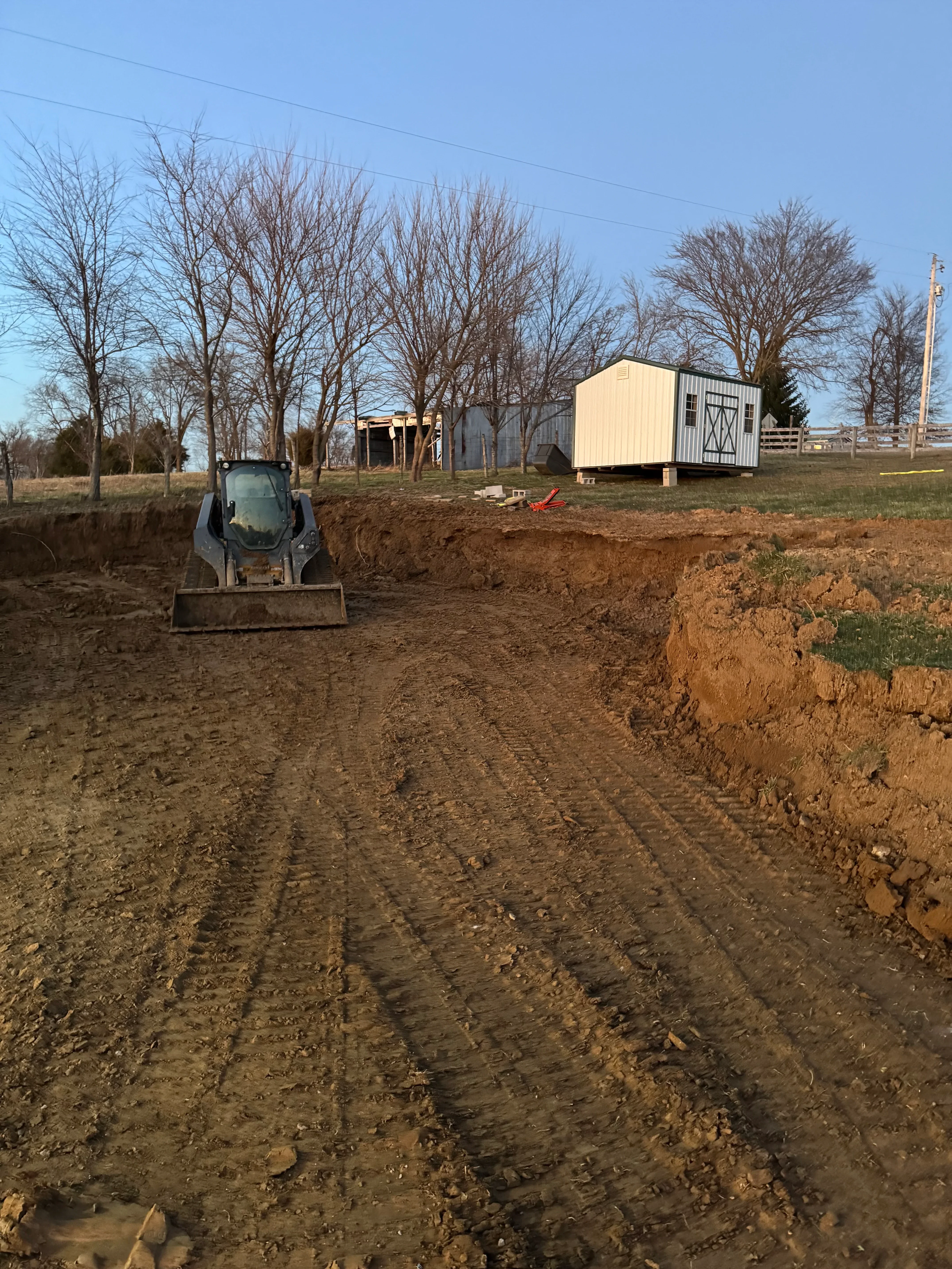 Excavated residential lot with graded driveway, compacted soil, and prepared building site